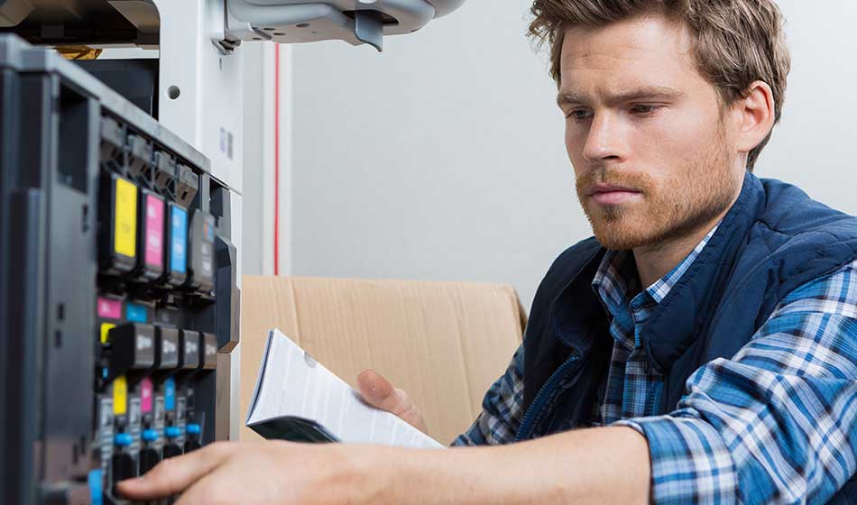 young male technician is repairing a printer at office